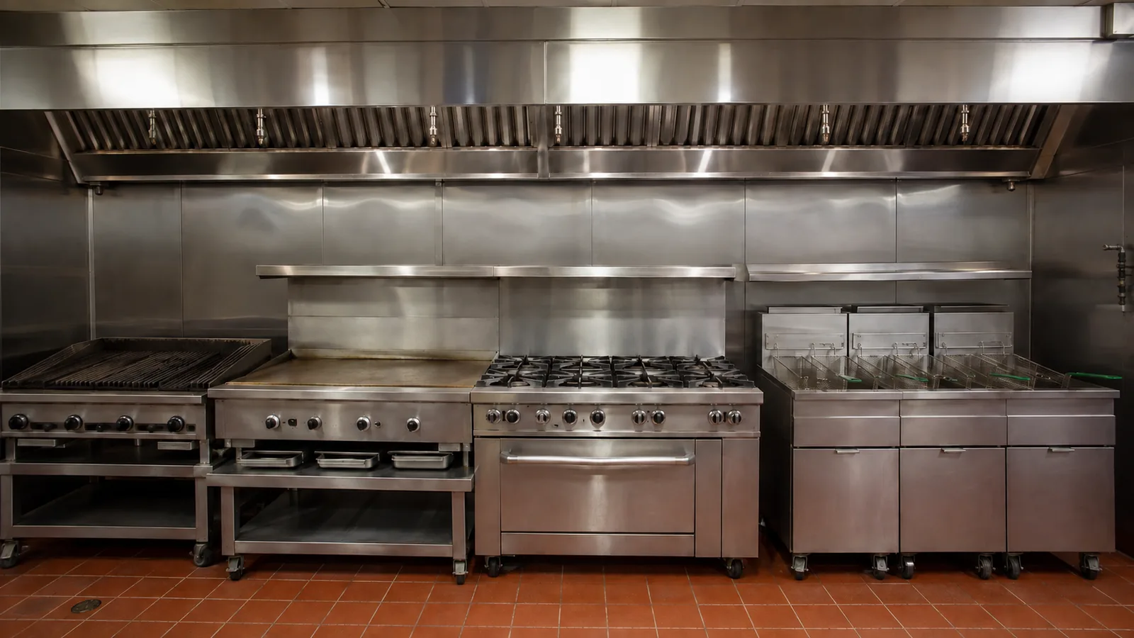 A long American restaurant cook line under one continuous hood: charbroiler, flat-top griddle, six-burner range and a bank of fryers.