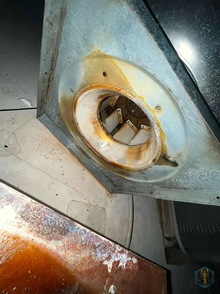 Exhaust fan opening before cleaning, with a thick amber ring of grease around the collar and heavy staining below.