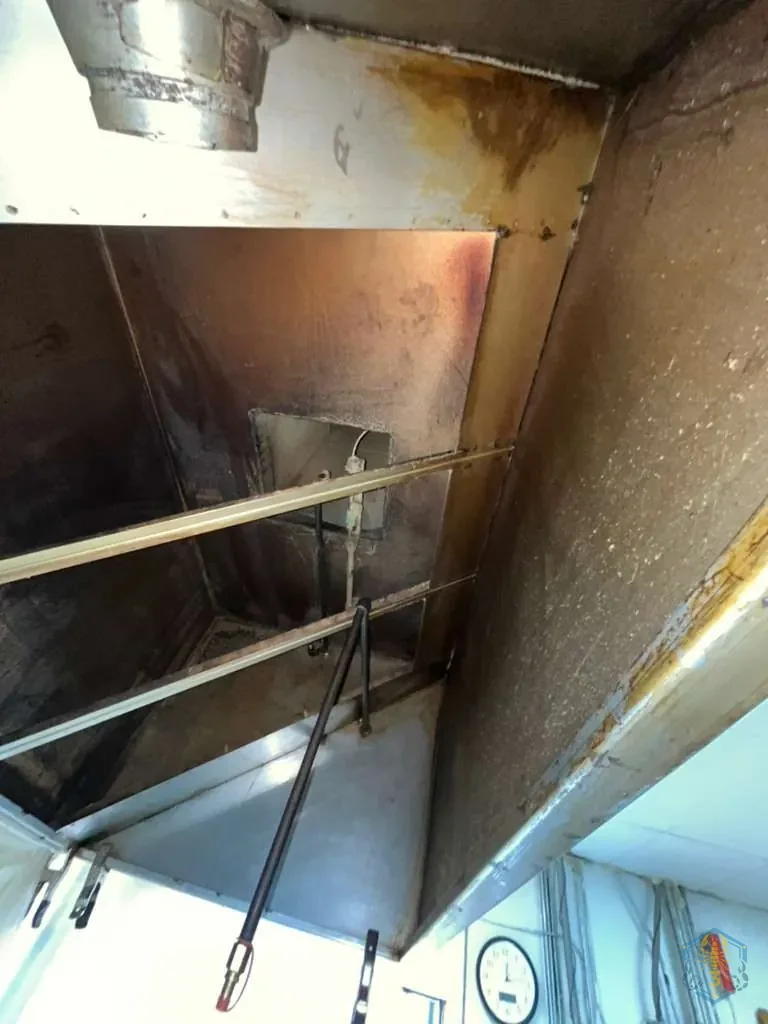 Hood interior before cleaning, showing grease build-up on the plenum wall and the filter support rails.