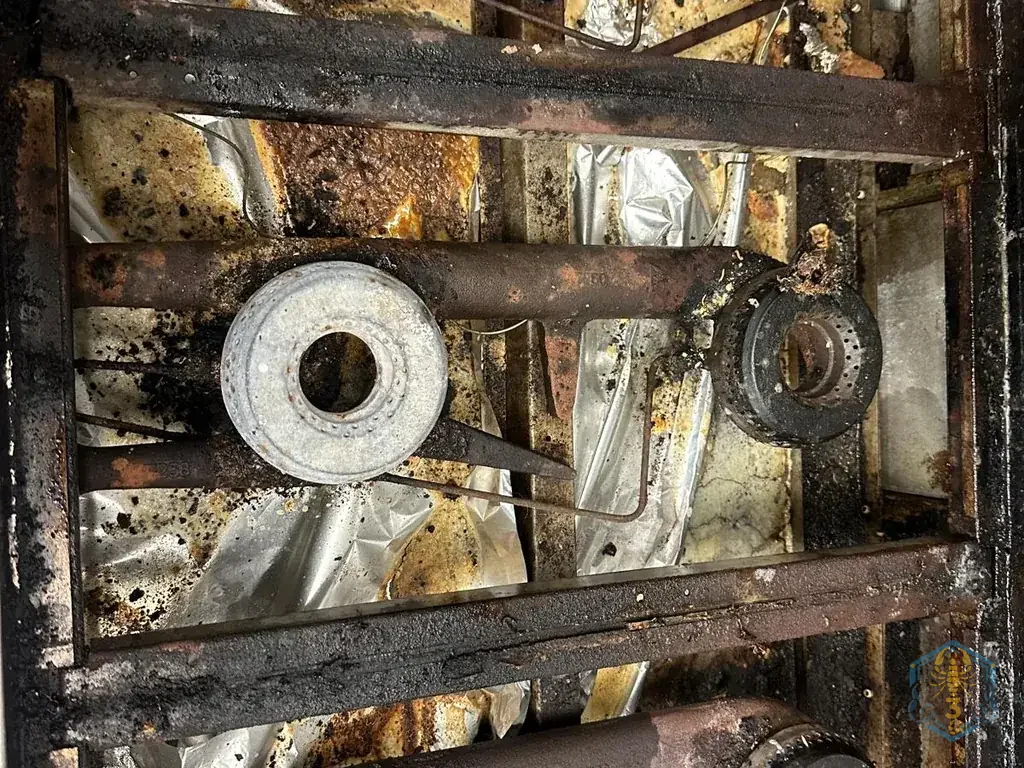 Inside a range with the grates off: burner rings, crumpled foil and years of carbon.