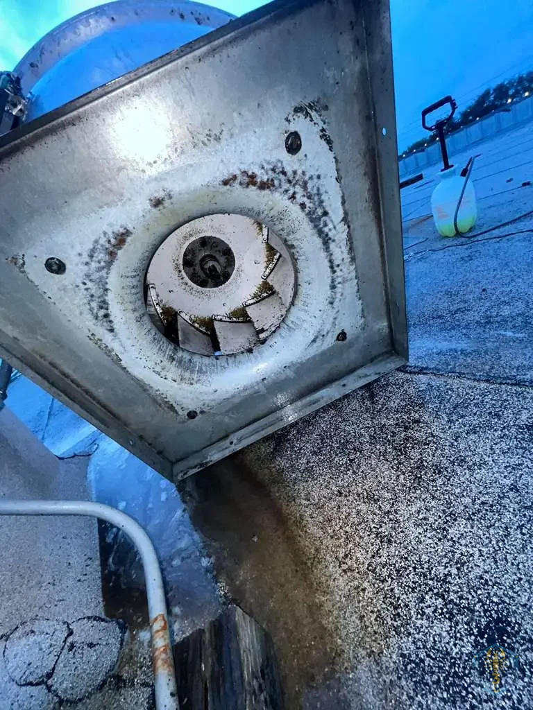 Grease staining running from an exhaust fan curb across the roof gravel — the damage a landlord bills the restaurant for.
